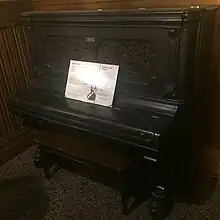 An old, black piano with a piece of paper on it.